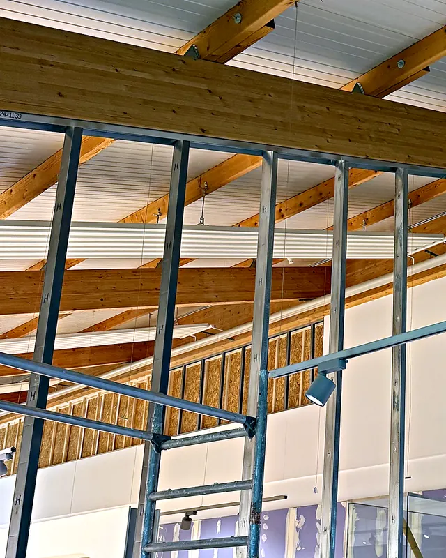 Metallständerwand im Aufbau unter einer Holzdachkonstruktion